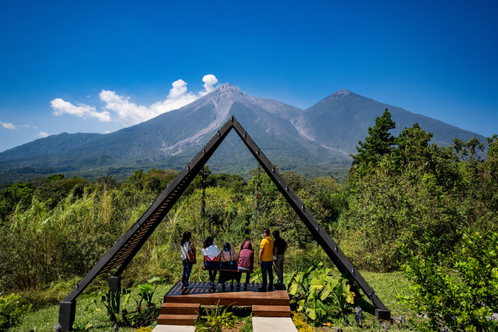 A group of people standing on a structure with a mountain range behind them. 