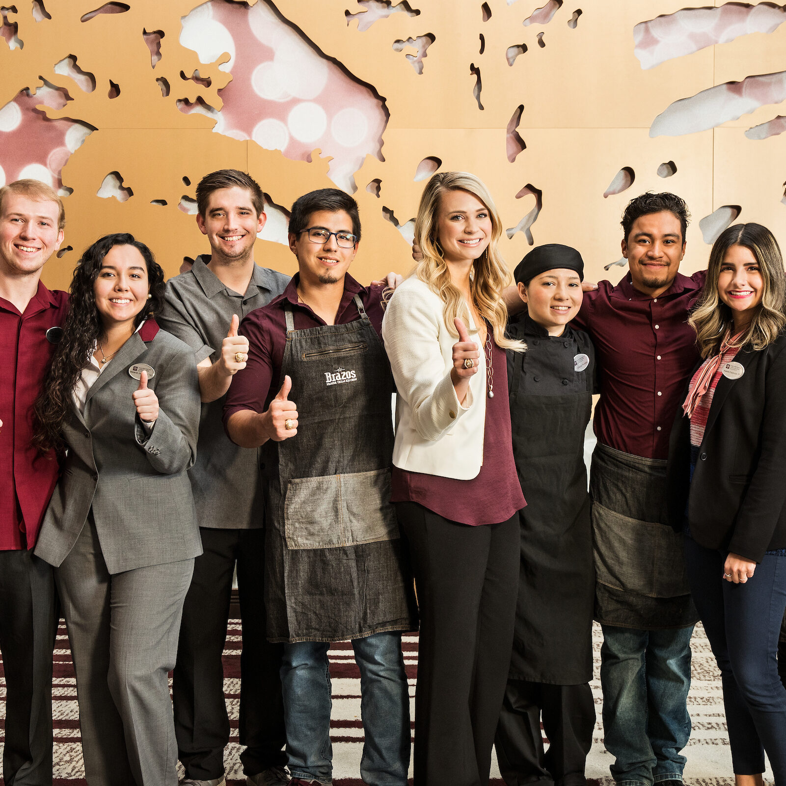Small group of students with their thumbs up, giving the gig 'em gesture.