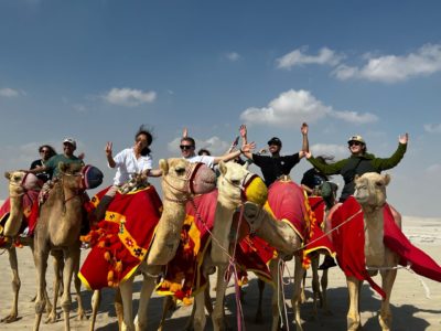 Students on a study abroad in Qatar riding camels.