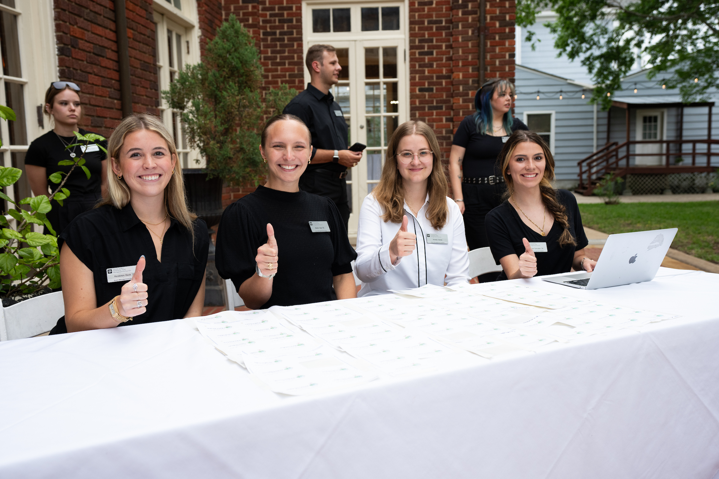 four female students greeting guests at an event
